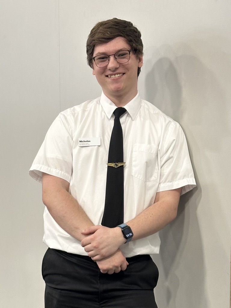 Nicholas Fason wearing a white shirt, black tie, and black pants, smiling for a portrait